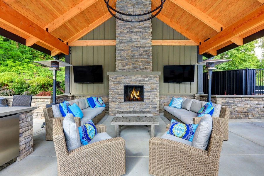 Outdoor entertainment area with two televisions, a fireplace, and plush furniture to sit and enjoy. 